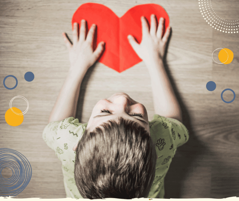 Photo taken from above of young boy holding a red paper heart (to illustrate tips on handling separation anxiety)