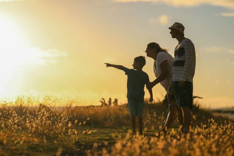Photo of two adults and one child in a field looking towards the sun to illustrate article on step-parenting tips