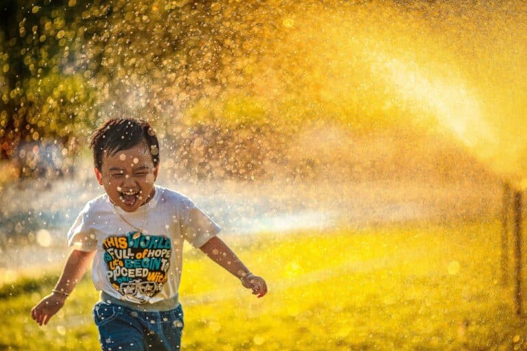 phot of happy child running through water to illustrate article on positive parenting