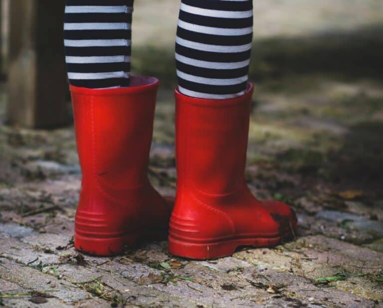 child playing outdoors in wet weather wearing wellington boots - ideas for outdoor play