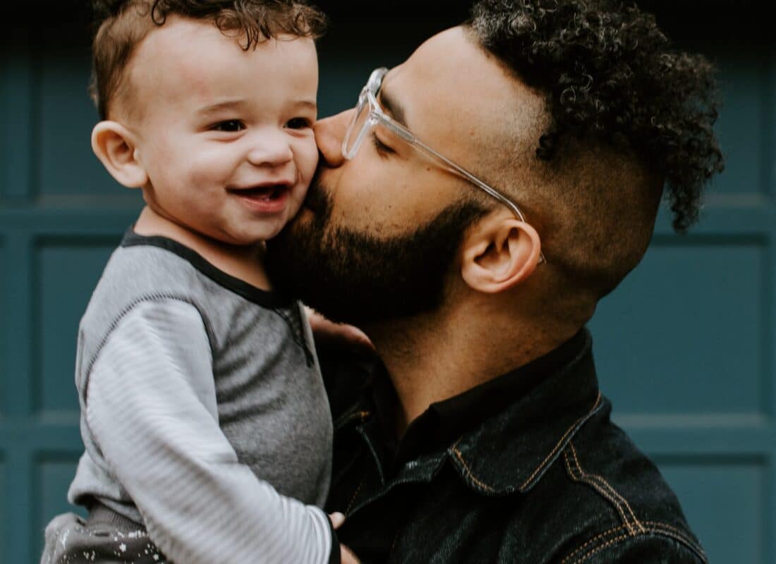 dad carrying toddler and kissing him on the cheek