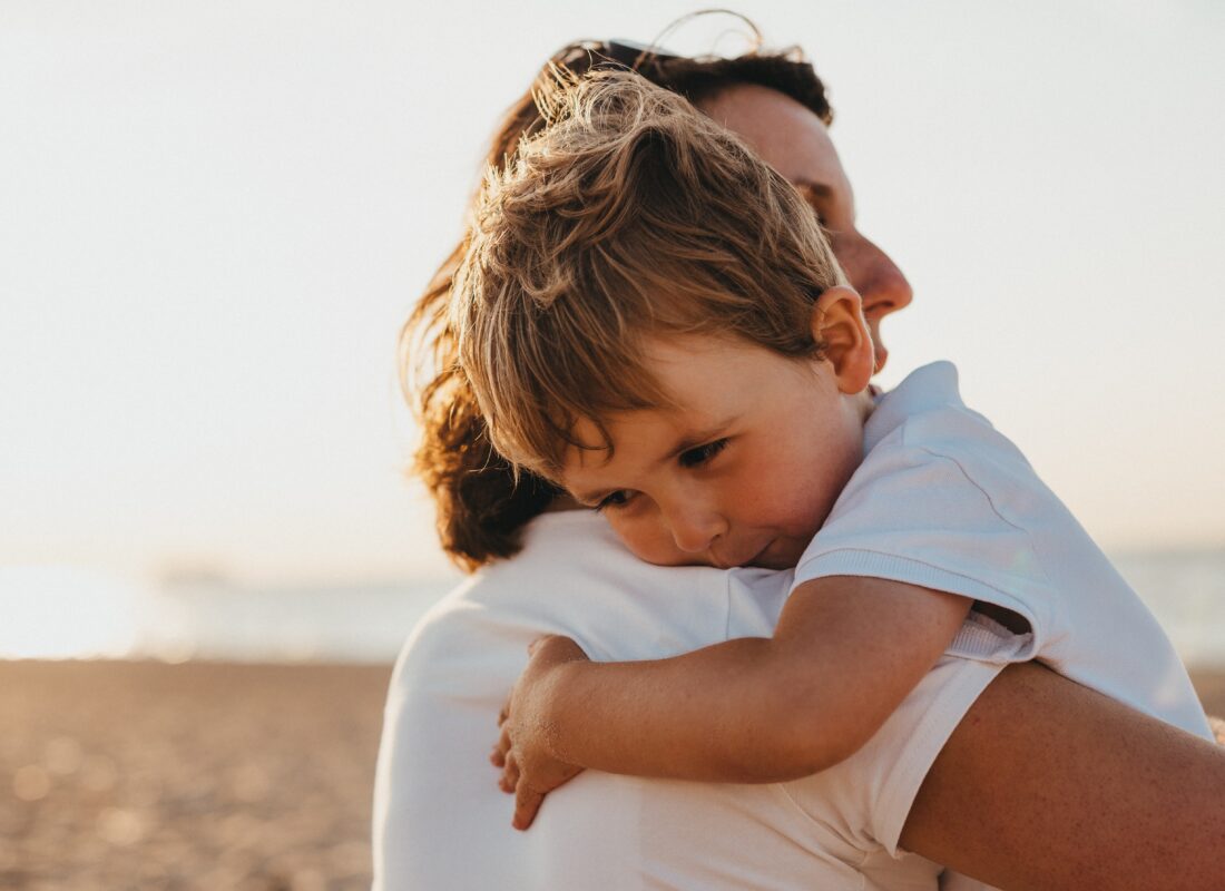 Photo of mother cuddling young child to illustrate article on talking to children about tragic events