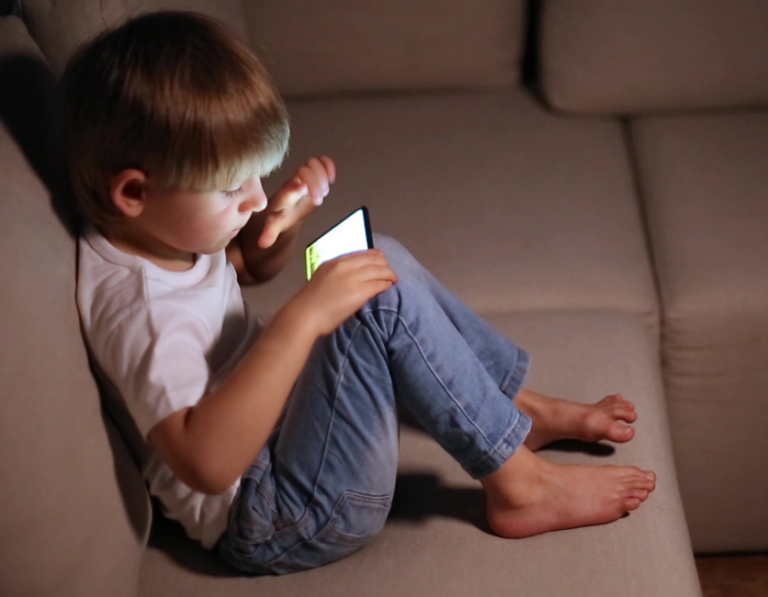 photo of child playing on phone to illustrate blog by parenting expert Anita Cleare on How much tech time is too much tech time?