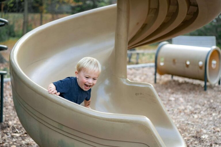 photo of child coming down a slide to illustrate blog post by parenting expert Anita Cleare on how 'moments to shine' help build children's self-esteem