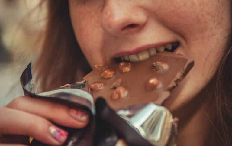 photo of teenager eating chocolate to illustrate article by parenting expert Anita Cleare on talking to a teenager about healthy eating without giving them body image anxiety