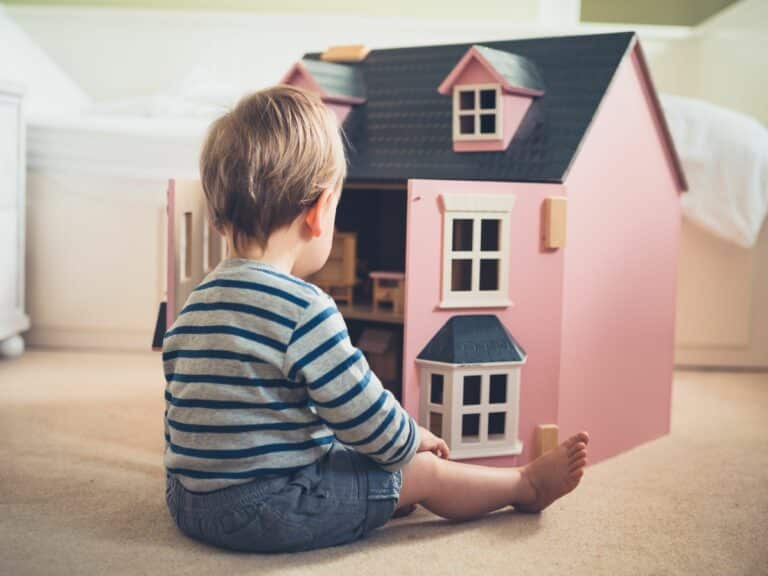 photo of young boy playing with a pink doll's house to illustrate article on why diverse and inclusive toys are important
