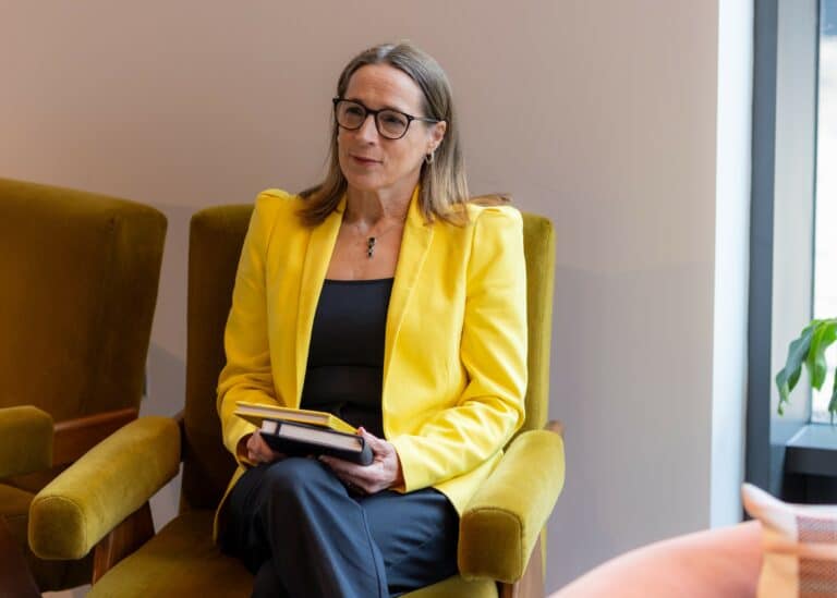 photo of parenting expert Anita Cleare sitting in a green chair wearing a yellow jacket