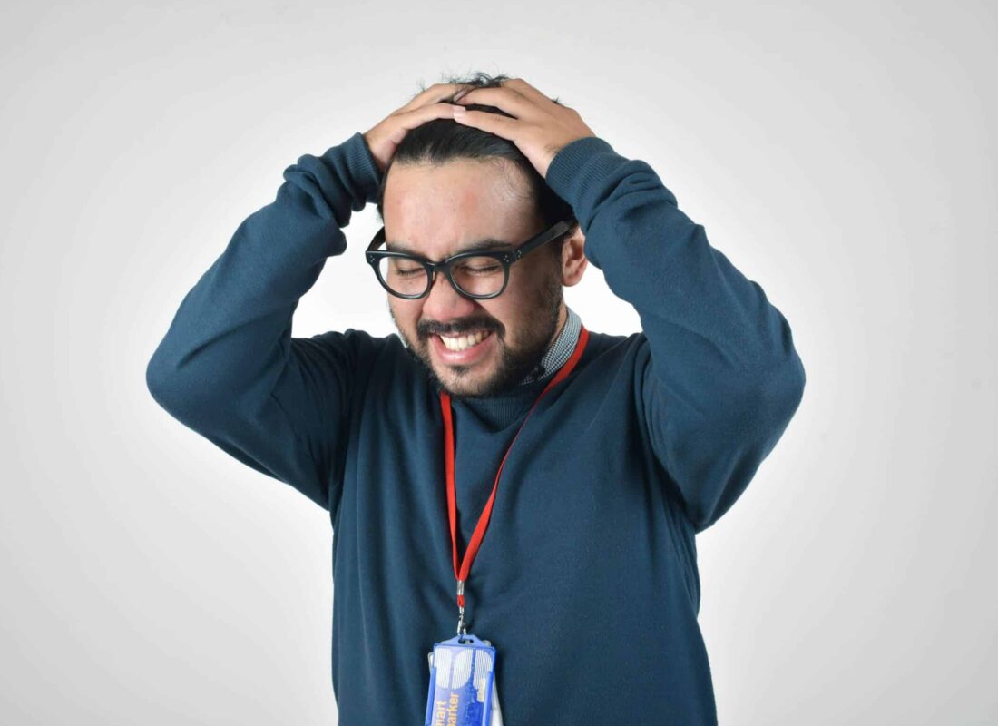 Photo of man with his hands on his head looking annoyed and exasperated