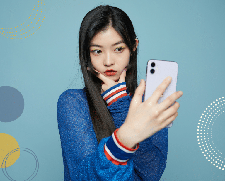 Photo of young asian girl taking a selfie and angling her face with her hand, to illustarte article on promoting positive body image in girls