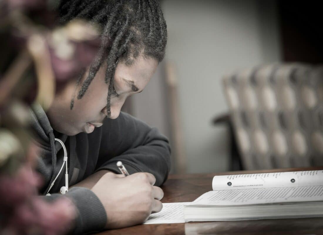 close up photo of teenage boy writing in an exercise book