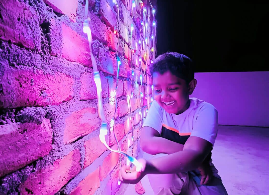 young boy with a big smile playing with lights in a sensory room to illustrate talk topic by parenting expert Anita Cleare on how to raise future-ready kids in the age of AI
